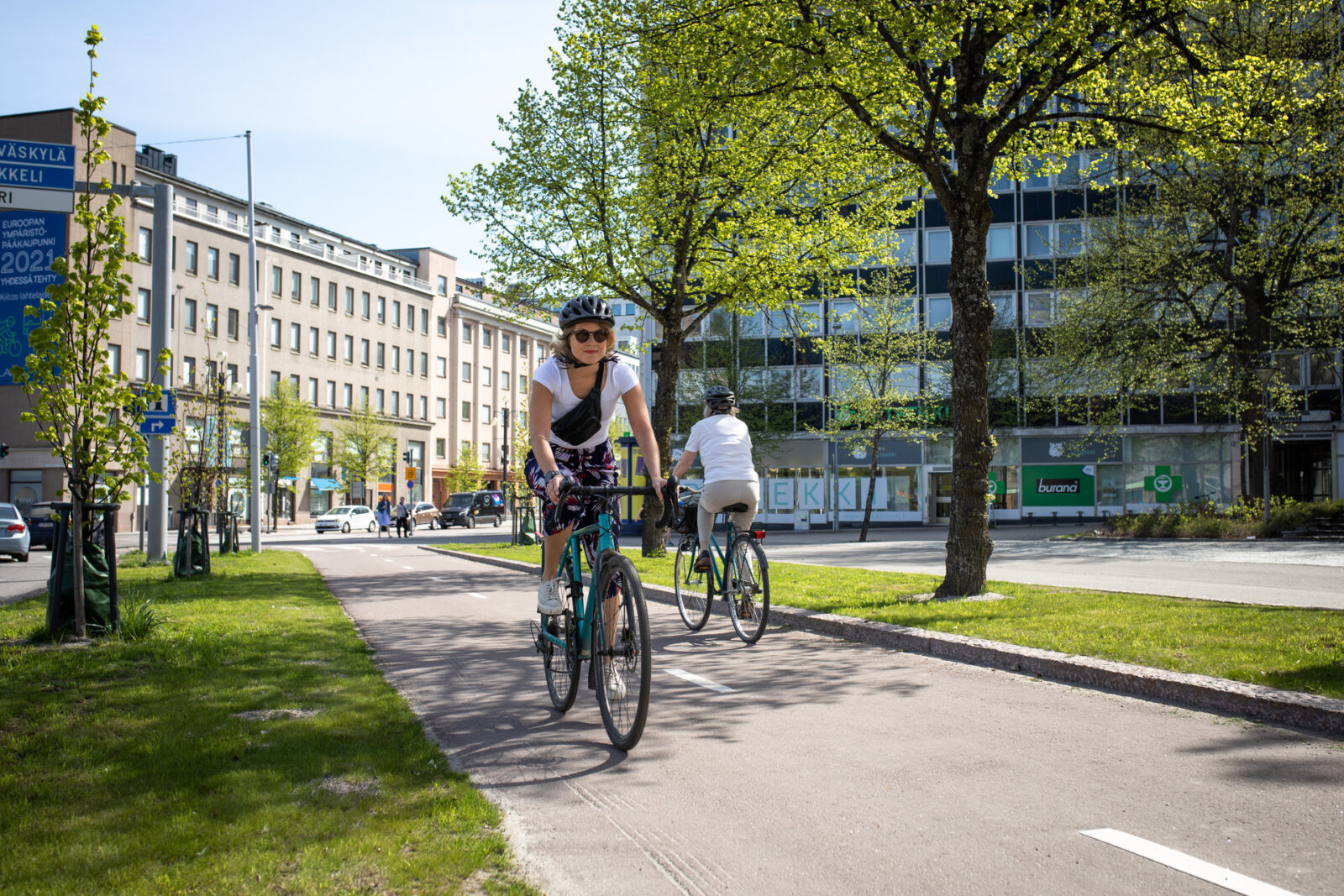 Pyöräiljöitä pyörätiellä. Taustalla kaupunkinäkymä.