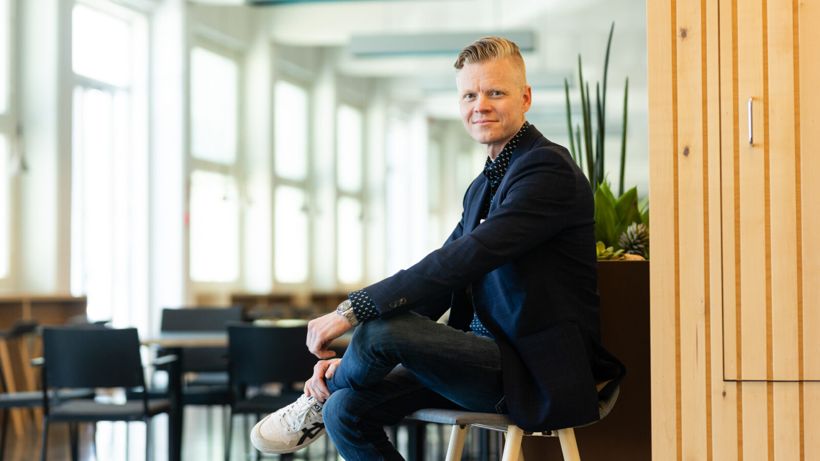 Harri Reiman istuu kampuksen käytävällä jakkaran päällä.