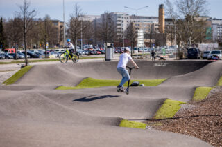 Kaksi lasta ajaa potkulaudoilla Ranta-Kartanon pumptrack-radalla.